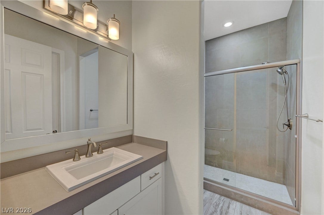 89 Olympia Chase Drive, Las Vegas, NV 89141 Clean lines and stone counters highlight this modern bathroom with a glass-enclosed walk-in shower.