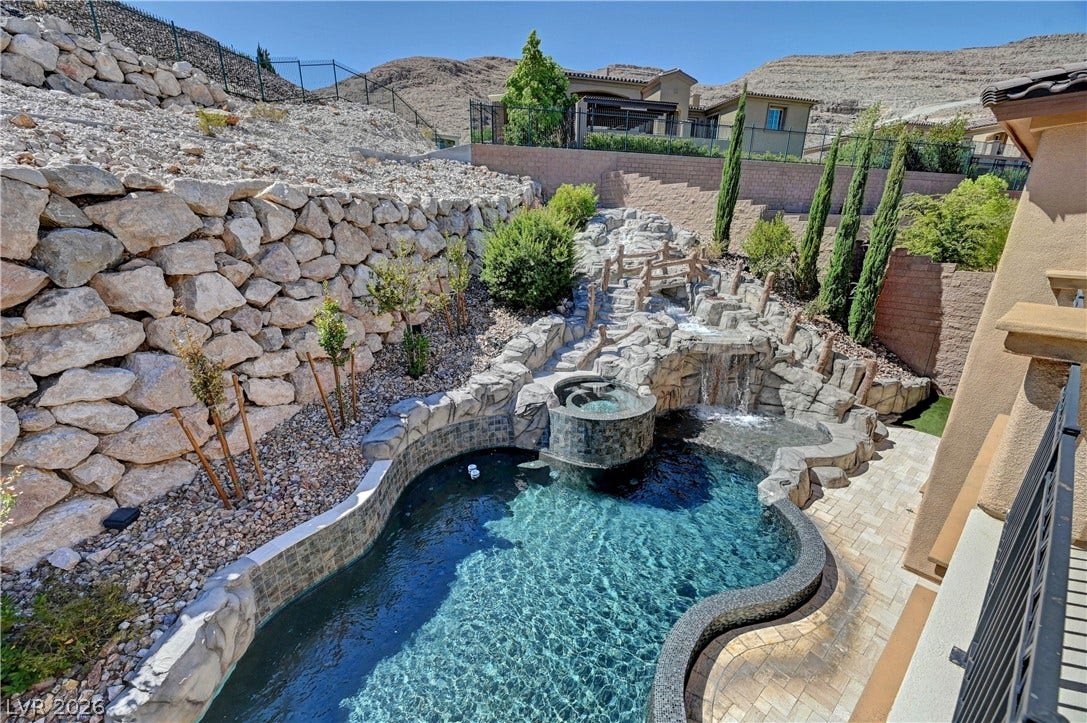 89 Olympia Chase Drive, Las Vegas, NV 89141 A custom rock waterfall cascades into this sparkling pool surrounded by rugged hillside stone walls.