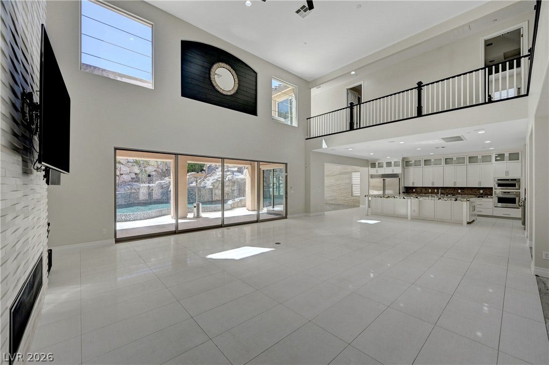 89 Olympia Chase Drive, Las Vegas, NV 89141 Massive sliding glass doors connect the soaring, tiled great room to a private outdoor pool.