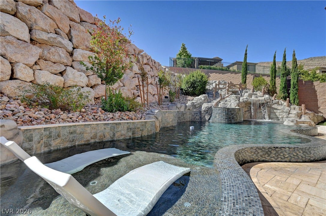 89 Olympia Chase Drive, Las Vegas, NV 89141 Dramatic rock formations and cascading waterfalls frame this custom backyard swimming pool.