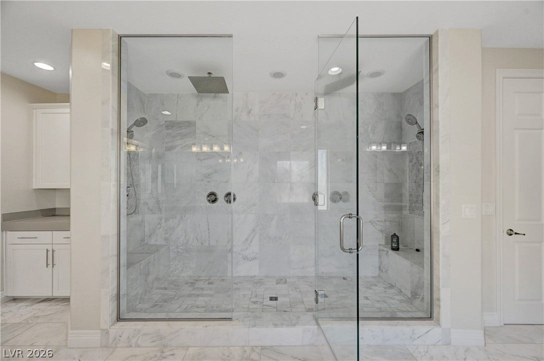 89 Olympia Chase Drive, Las Vegas, NV 89141 Floor-to-ceiling marble tile and glass doors elevate this sprawling walk-in shower.