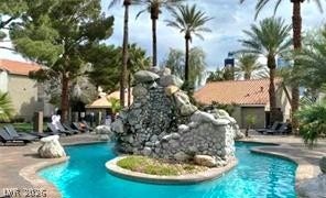 Lush tropical landscaping surrounds a sparkling resort-style pool with a dramatic stone waterfall feature.