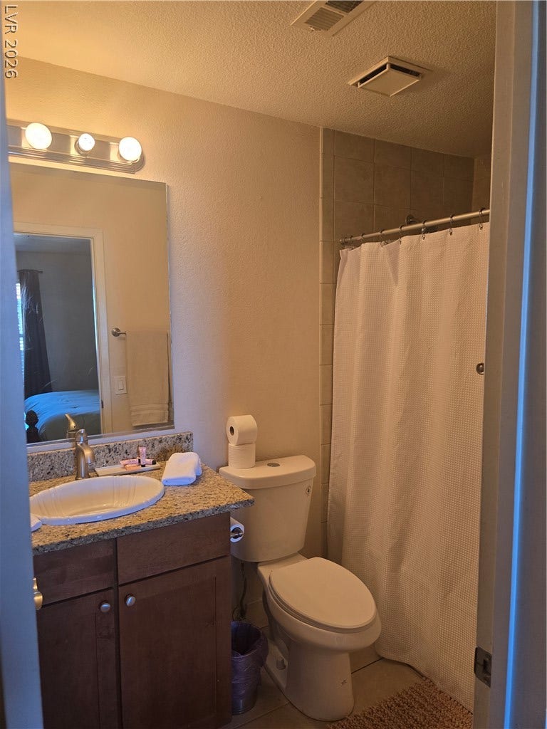 A classic tiled tub enclosure sits adjacent to a granite-topped vanity.