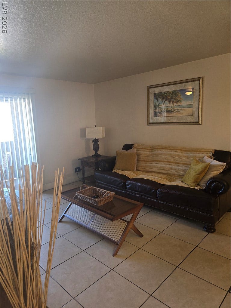 Durable tile flooring runs throughout this versatile living space featuring sliding door access.
