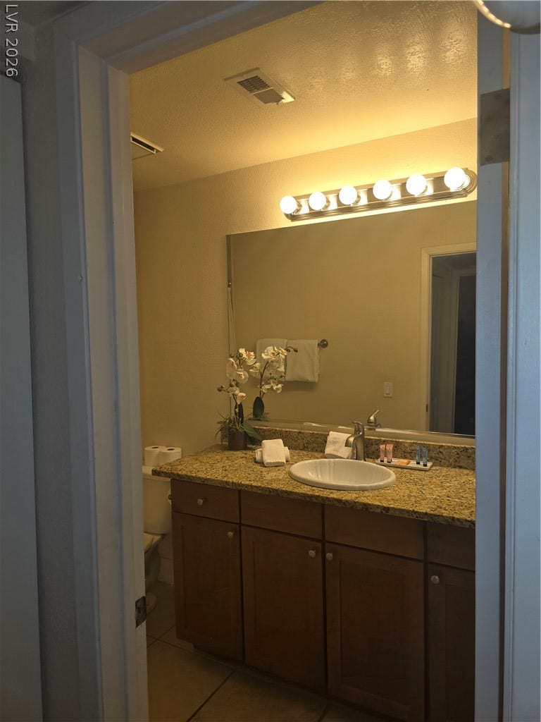 Rich granite countertops pair with warm wood cabinetry in this inviting bathroom vanity area.