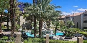 Lush palm trees surround a sparkling resort-style pool with an integrated rock waterfall feature.