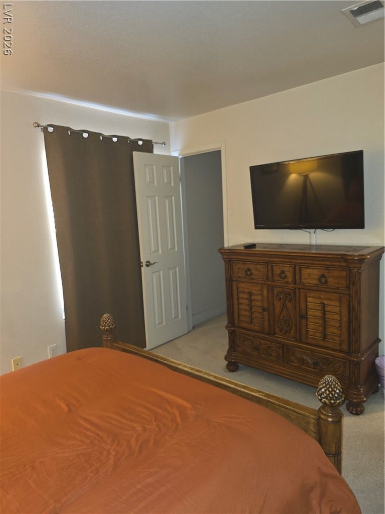 Plush carpeting underfoot complements the neutral walls in this restful sleeping space.