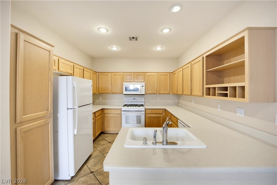 Ample wooden cabinetry and sprawling light countertops maximize storage and workspace in this functional kitchen.