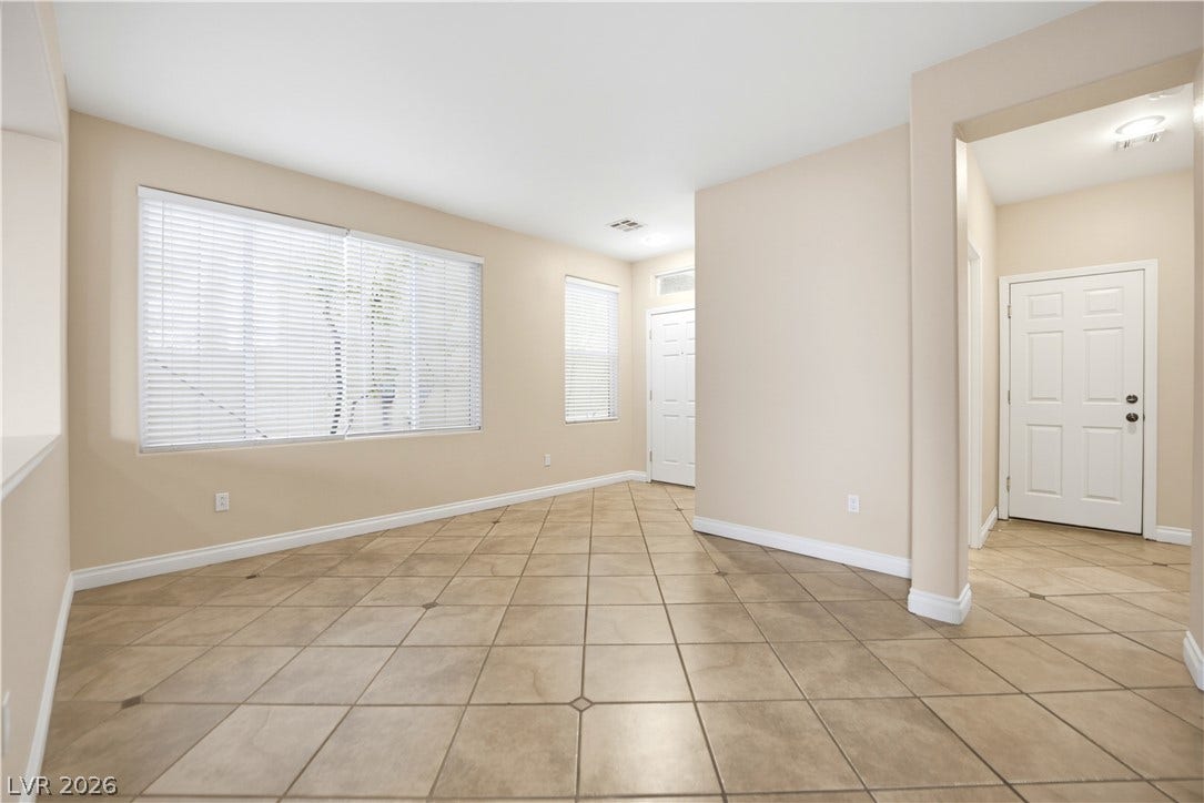 Tiled flooring and large windows with blinds define this versatile open living space.