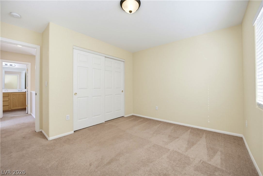 Soft carpeting pairs with neutral walls in this versatile bedroom complete with sliding closet doors.