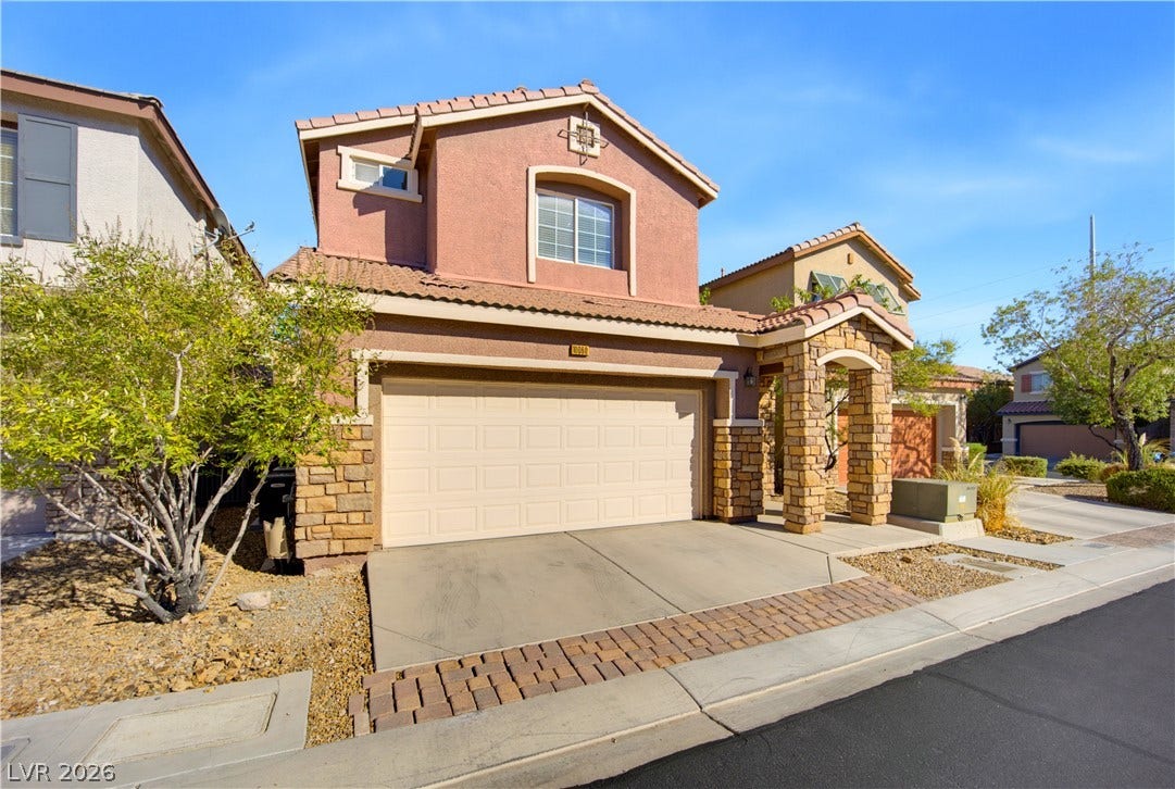 Earth-toned stucco and stone accents define this two-story exterior featuring a tile roof.