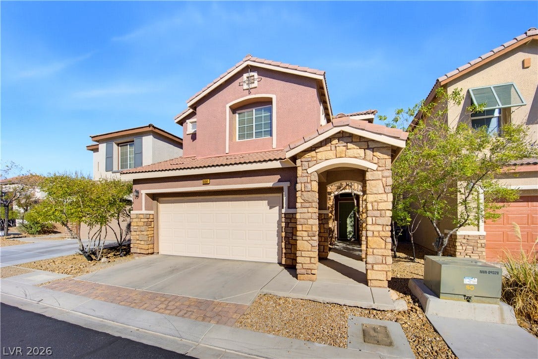 Stone accents and a covered entryway elevate the facade of this multi-level stucco home.