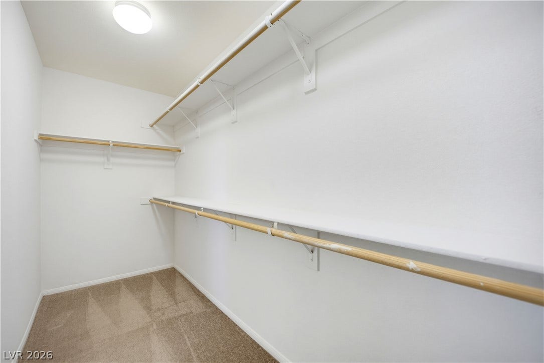 Ample built-in shelving and hanging rods maximize storage in this carpeted walk-in closet.