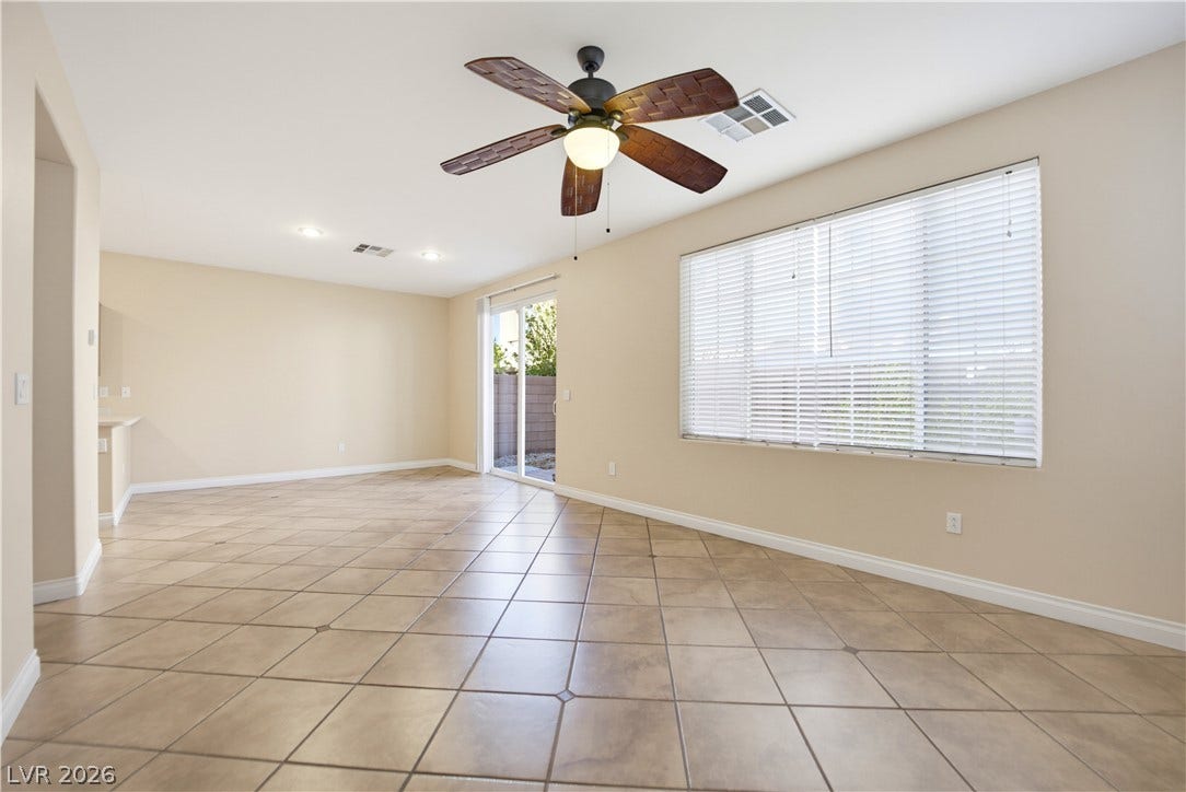 Ceramic tile floors and a wide window with blinds define this open living space.