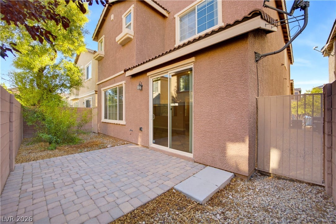 A neat paver patio coordinates beautifully with the stucco exterior and sliding glass door entrance.