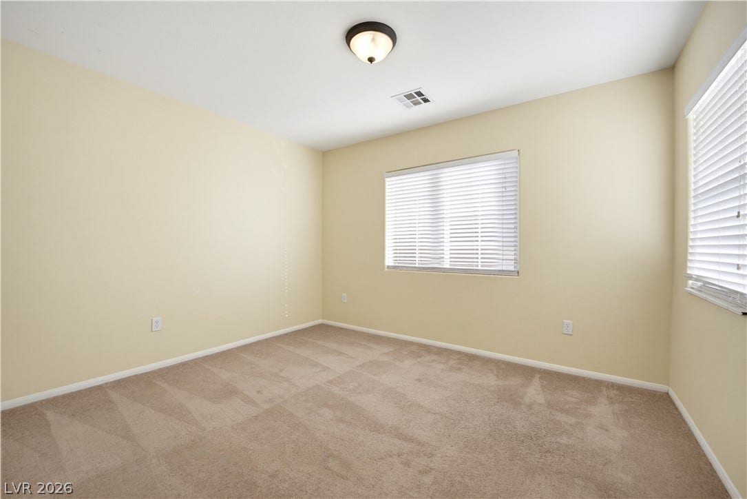 Plush wall-to-wall carpeting and multiple windows create a comfortable, sunlit retreat.