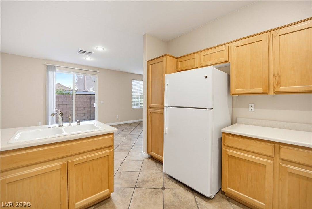 Natural wood cabinetry and neutral tile flooring define this functional cooking space.