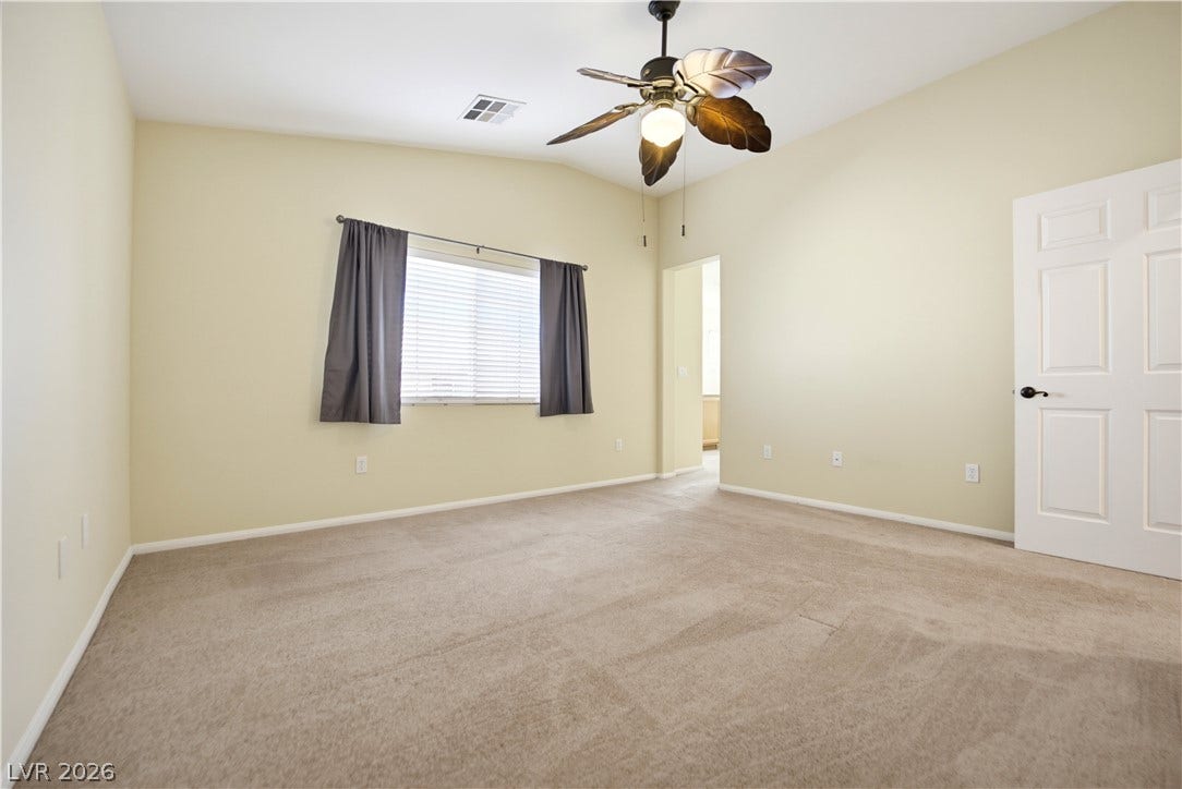 Vaulted ceilings and soft carpeting create a serene and inviting atmosphere in this bedroom.