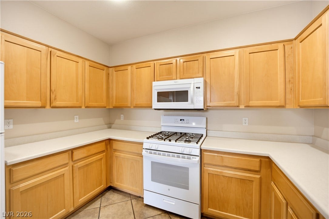 Ample wooden cabinetry and neutral countertops anchor this well-proportioned kitchen space.