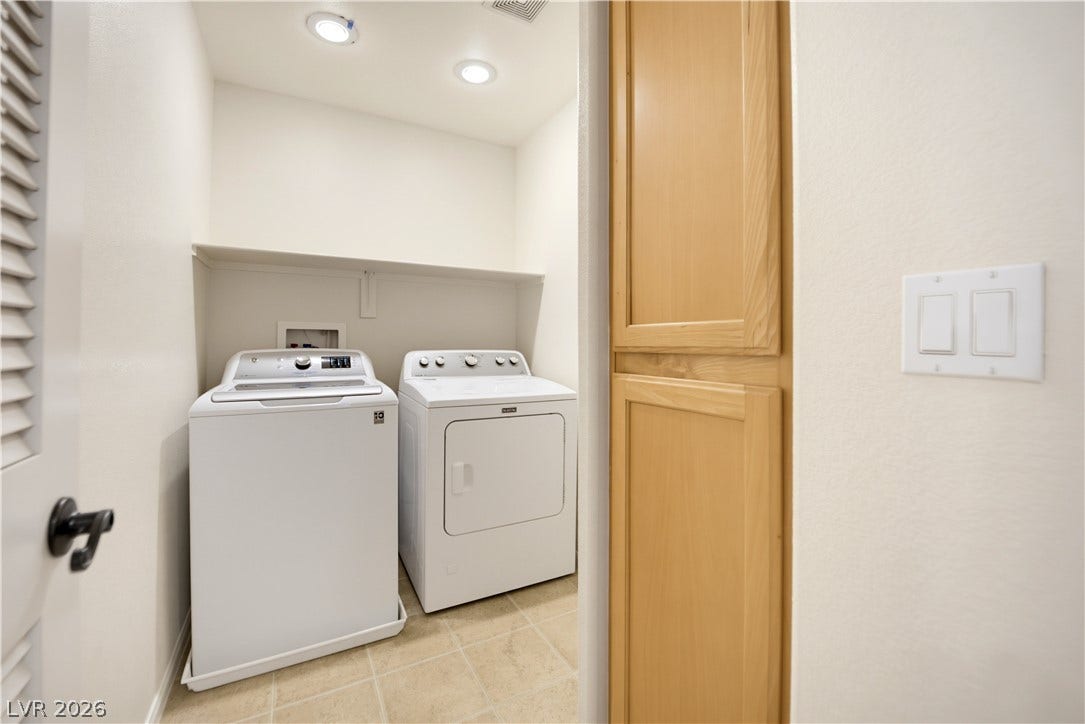 An organized laundry closet features built-in cabinetry and practical tile flooring.