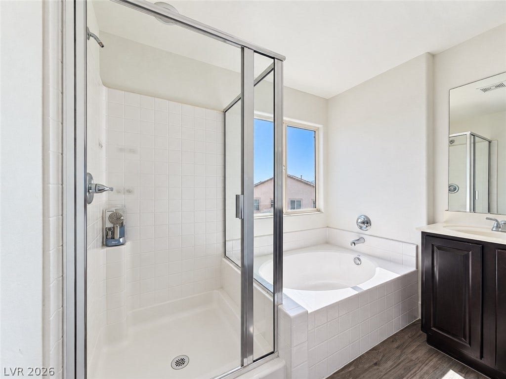 2321 Breckle Key Avenue, North Las Vegas, NV 89081 A glass-enclosed shower stands adjacent to a deep soaking tub and dark vanity cabinet.