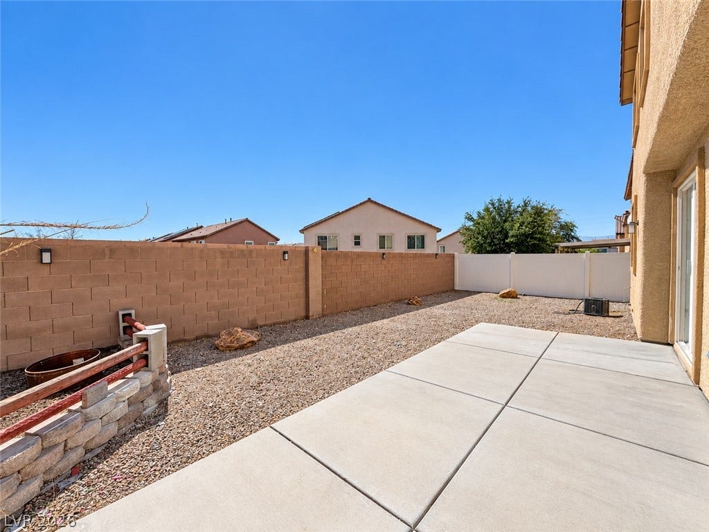 2321 Breckle Key Avenue, North Las Vegas, NV 89081 An enclosed backyard features a clean concrete patio alongside low-maintenance gravel landscaping.