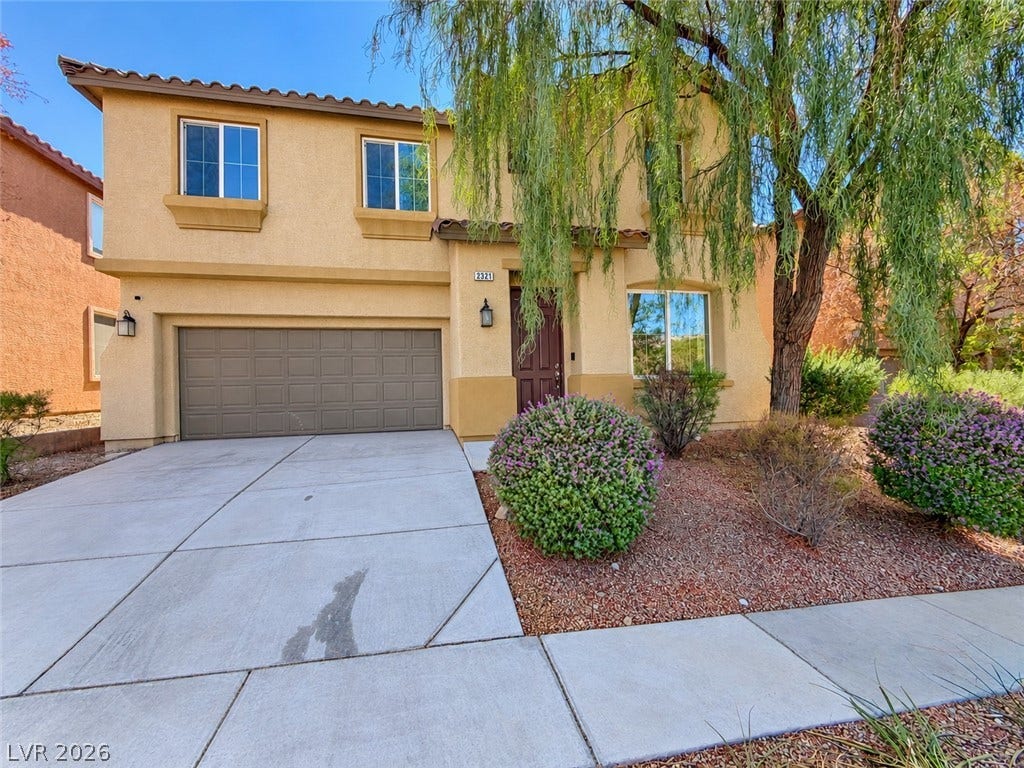 2321 Breckle Key Avenue, North Las Vegas, NV 89081 Mature trees shade the concrete driveway leading to a classic stucco home with tiled roof.