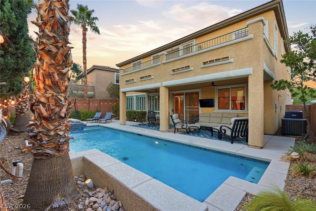 A sparkling swimming pool highlights this backyard oasis with a covered patio.