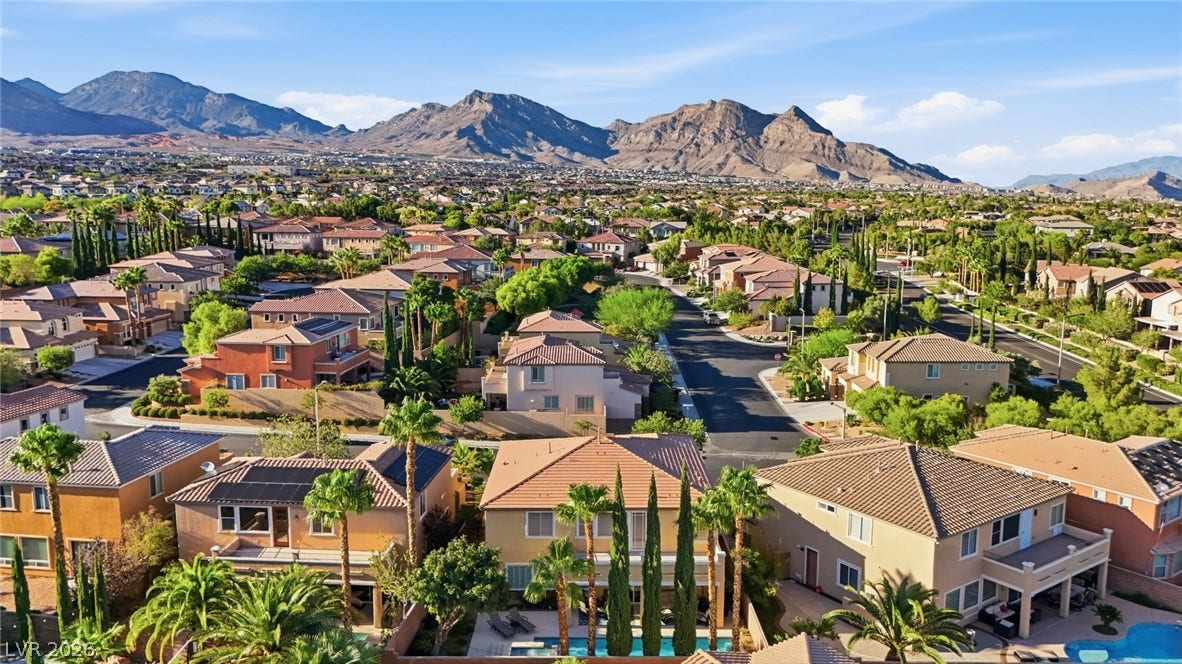 Dramatic mountain backdrops frame a peaceful residential neighborhood of modern tile-roof homes.