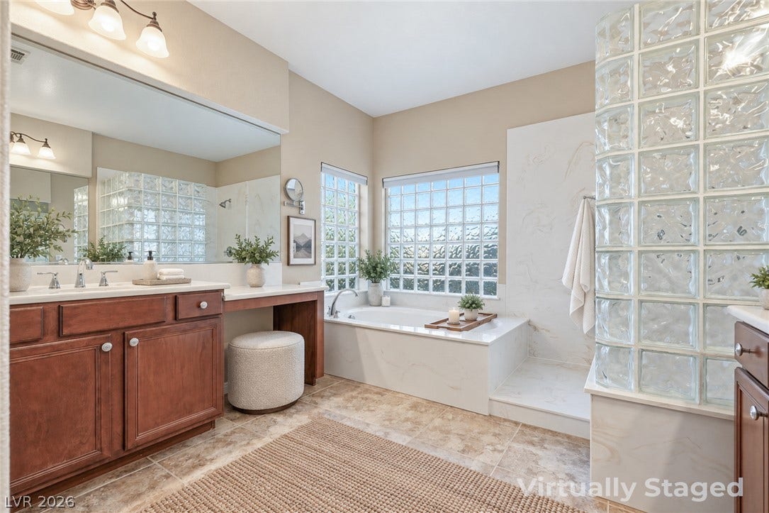 A glass block wall highlights the walk-in shower alongside a soaking tub and tile floors.