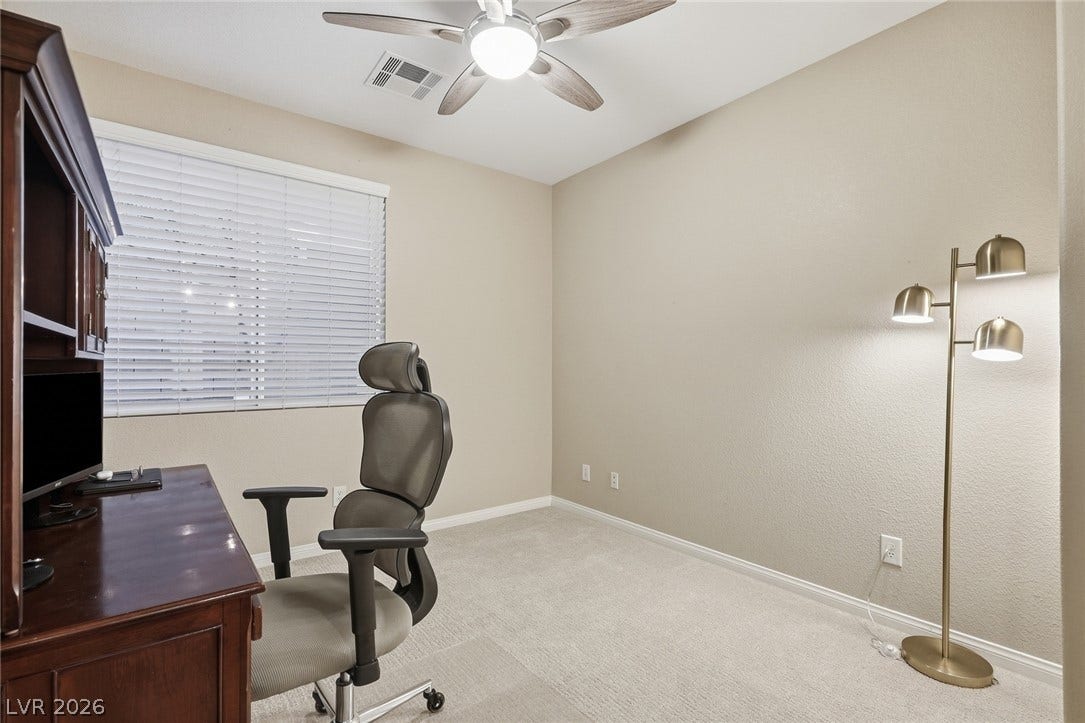 Downstiars bedroom- A quiet work space features wall-to-wall carpeting and a wide window with integrated blinds.