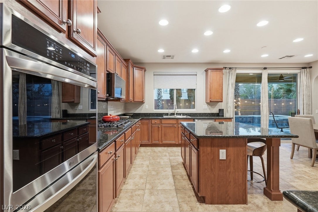 Granite countertops and rich wood cabinetry anchor this spacious kitchen over tile flooring.