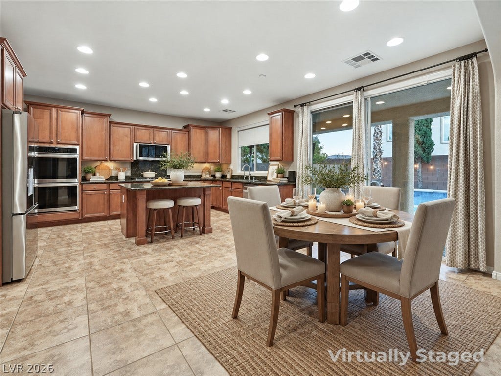 Granite counters and rich wood cabinetry complement the tile flooring in this open-concept kitchen.