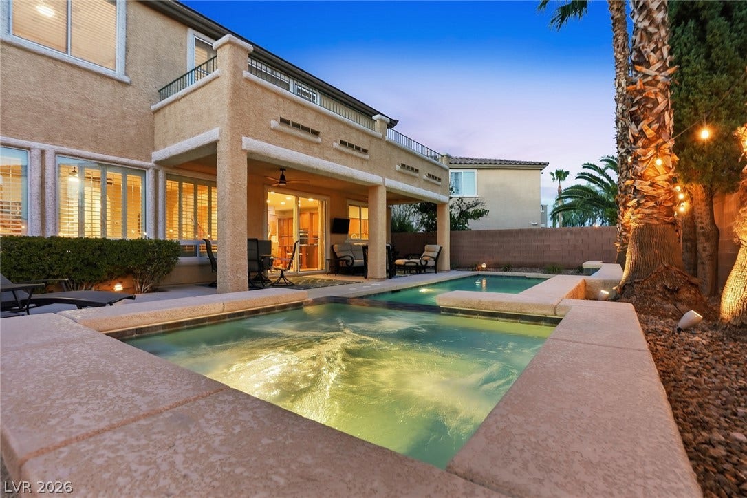 An inviting backyard oasis features a sparkling pool and spa set against a stucco exterior.
