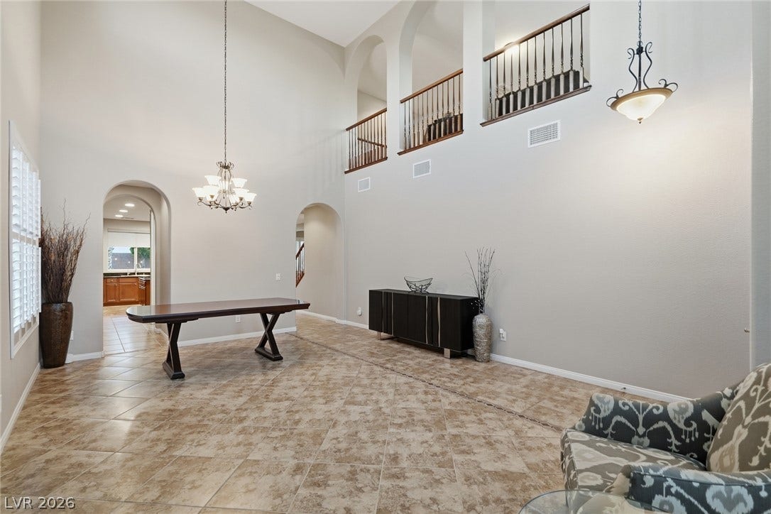 Double-height ceilings and arched architectural details create a grand impression in this tiled living area.