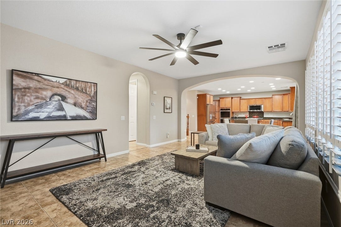 An arched doorway frames the adjacent kitchen from this tile-floored living area.