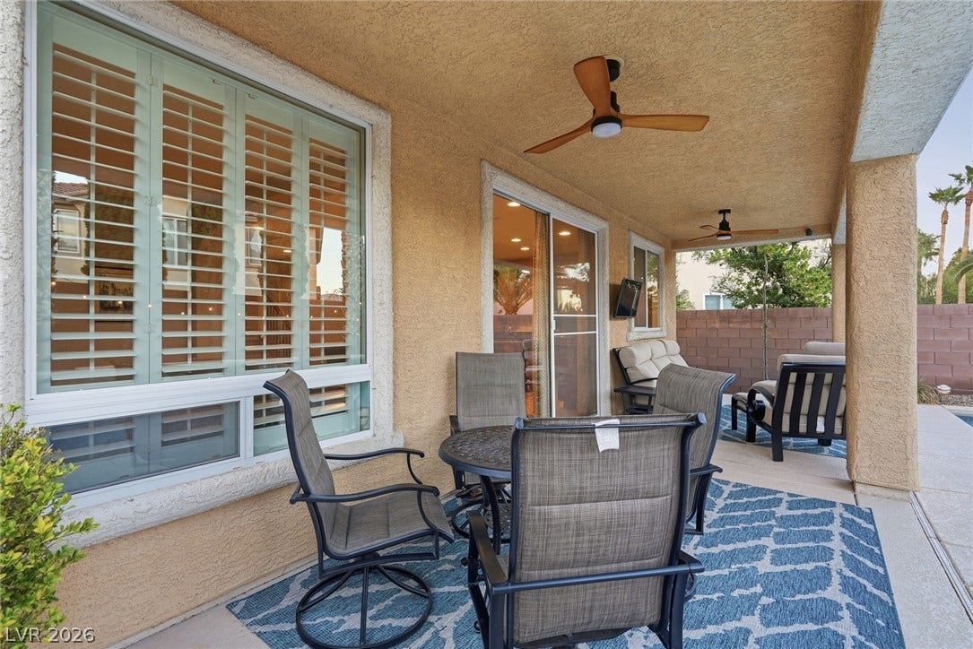 A sheltered concrete terrace sits beneath a finished stucco ceiling alongside large windows.