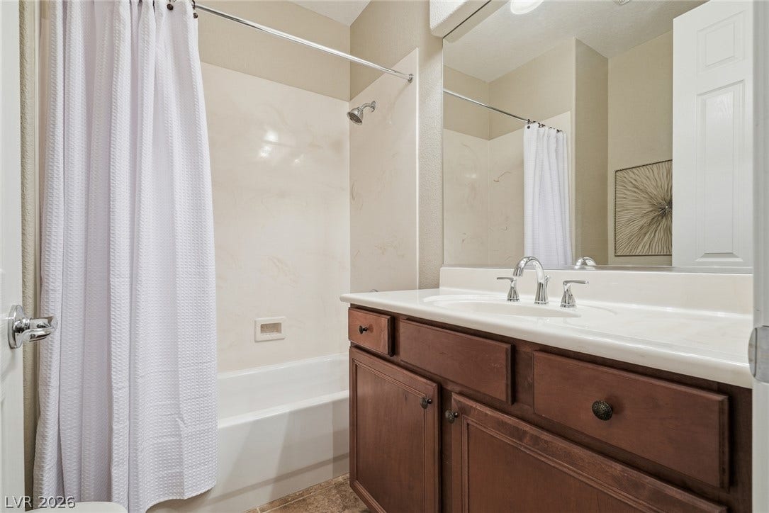 Downstairs Full Bath- A classic wood vanity and integrated sink sit adjacent to the tub shower combination.
