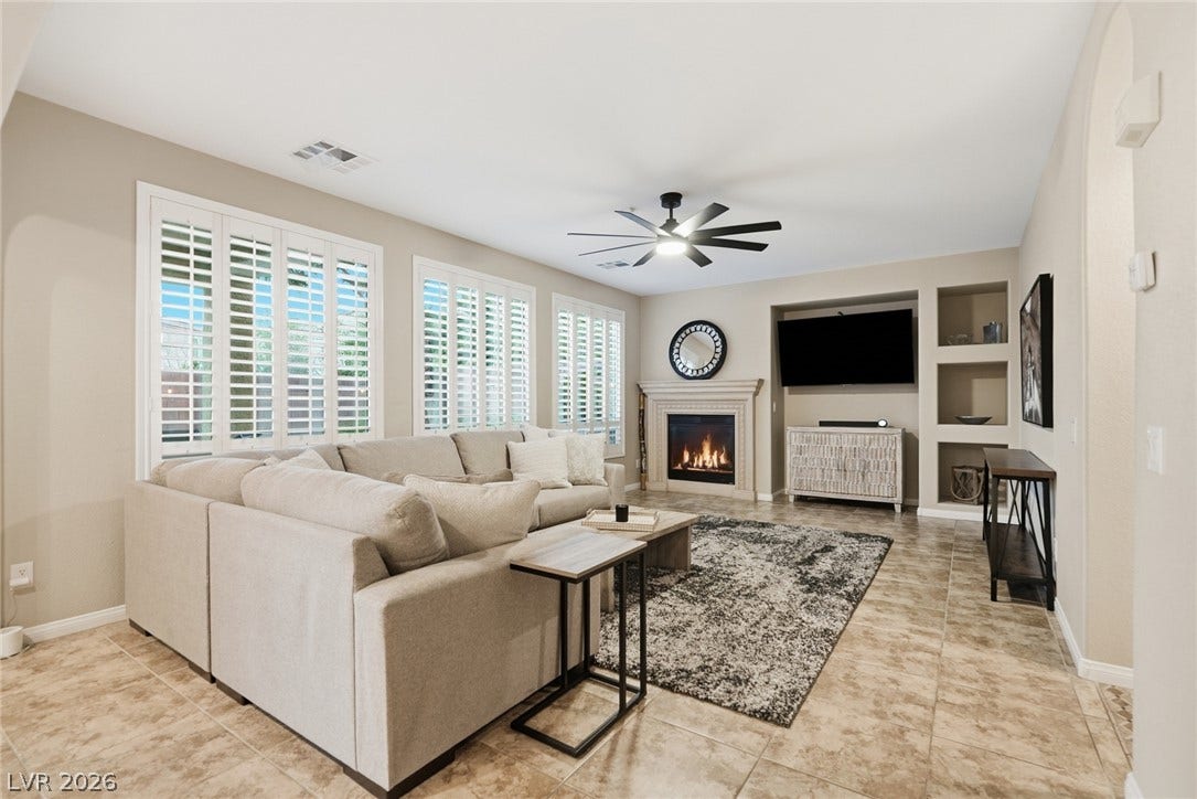 An inviting fireplace and built-in shelving complement the warm tile flooring in this living room.