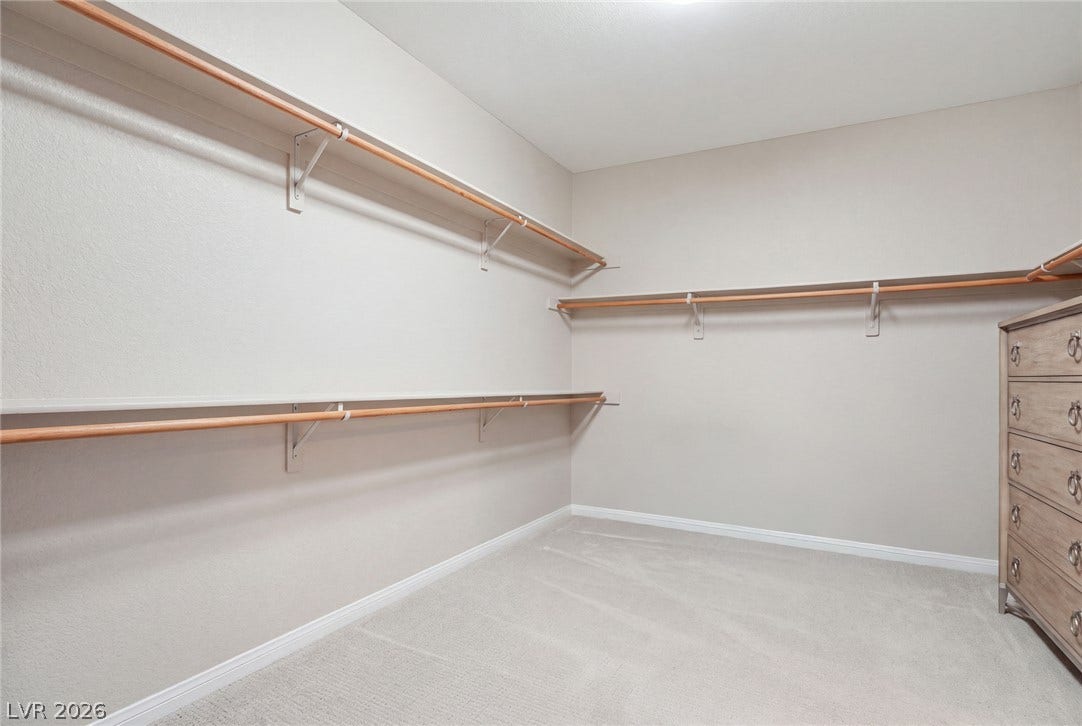 Ample built-in shelving and soft carpeting define this spacious walk-in closet.