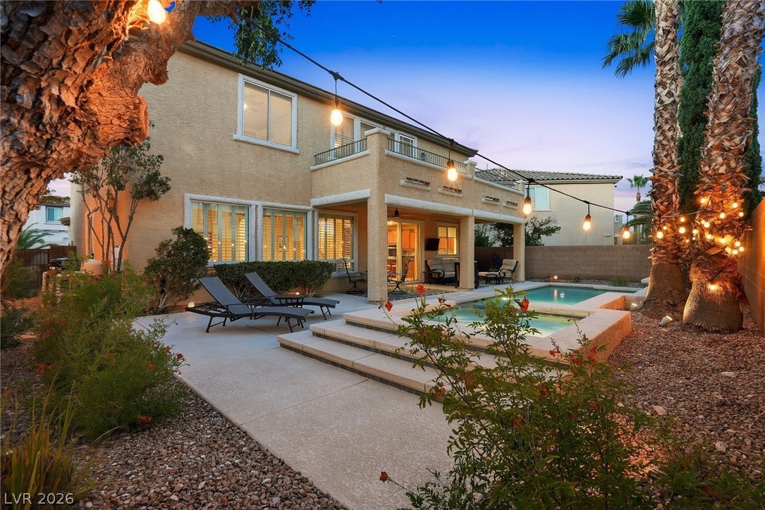 An inviting backyard oasis features a shimmering pool and spa adjacent to a covered patio.