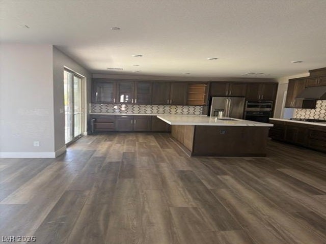 Rich wood cabinetry and a generous central island anchor this spacious, light-filled kitchen design.