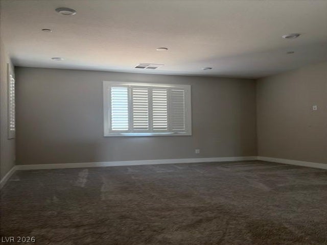 Recessed lighting illuminates this versatile space featuring plush carpeting and plantation shutters.