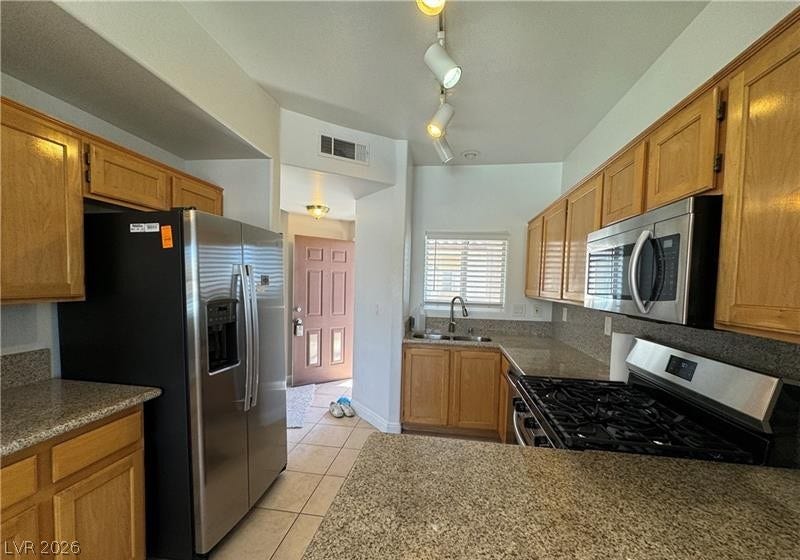 Warm wood cabinetry and granite countertops frame a functional layout with stainless steel appliances.
