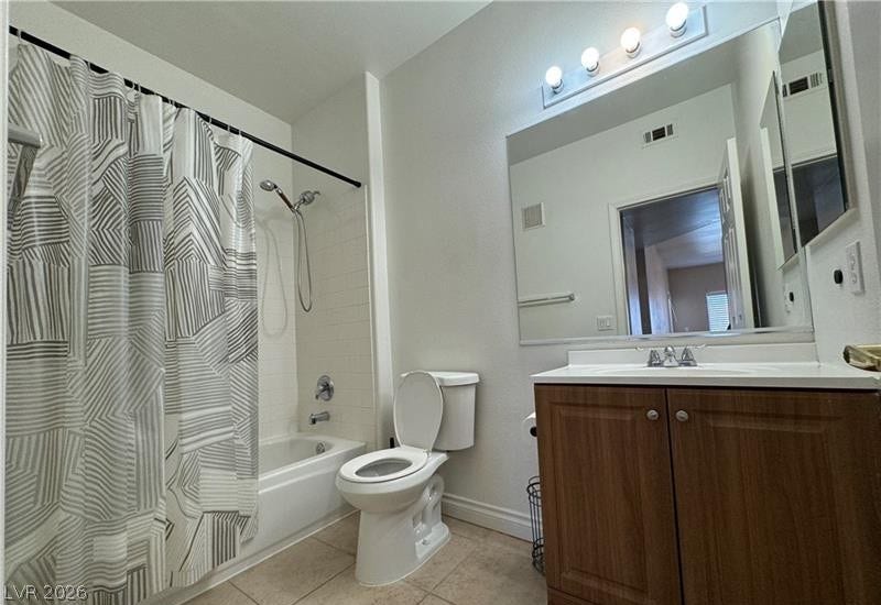 Clean tiling and a wood vanity define this functional bathroom space.