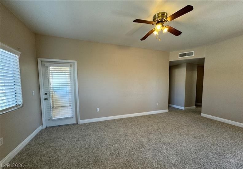 An open and versatile living space displays neutral textured carpeting and access to the outdoors.