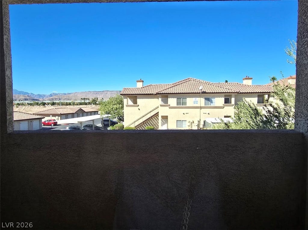Distant mountains frame the neighborhood view from this covered stucco balcony.