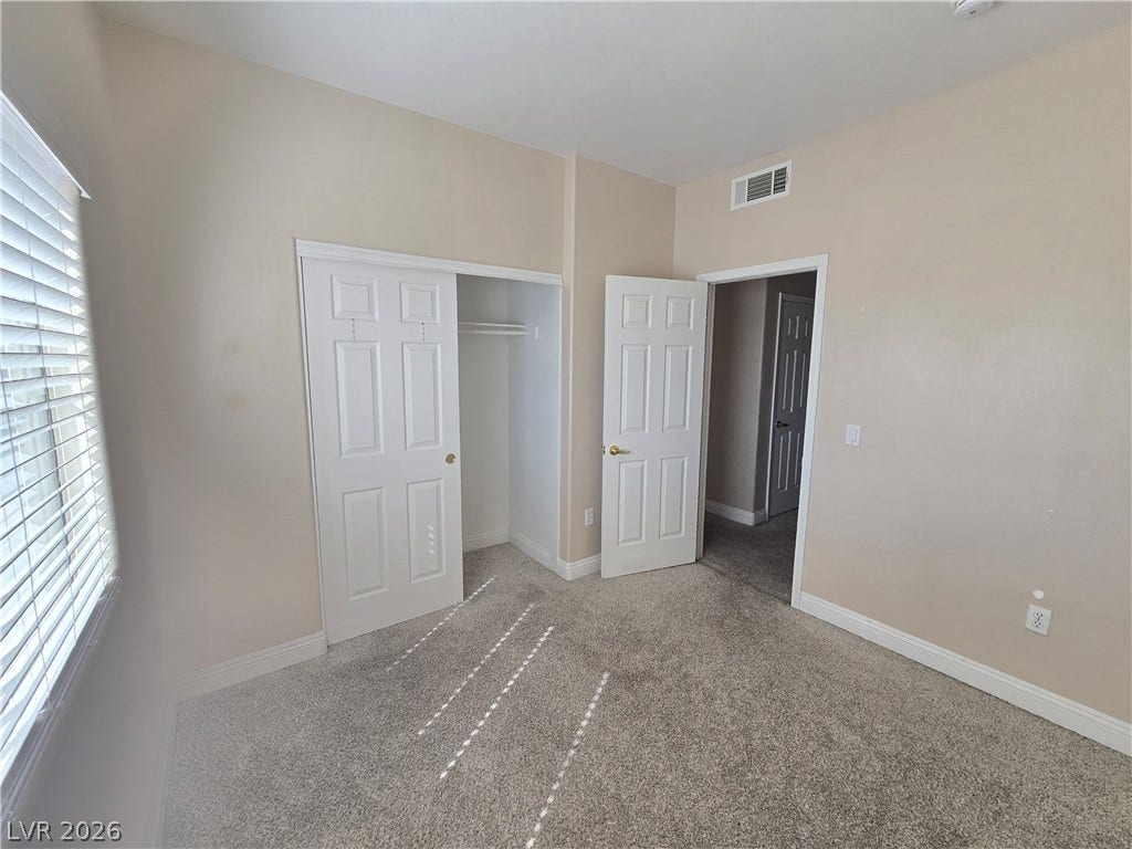 Soft carpeting pairs with a functional closet layout in this comfortable bedroom space.