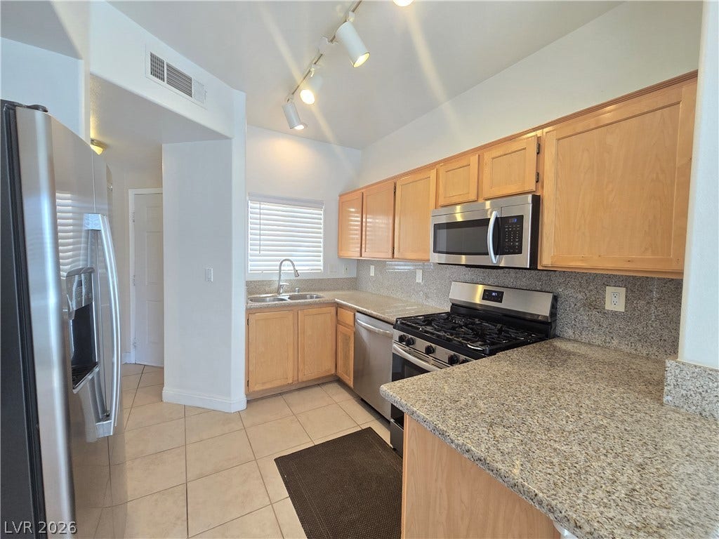 Warm wood cabinetry pairs with stone countertops in this well-appointed kitchen.