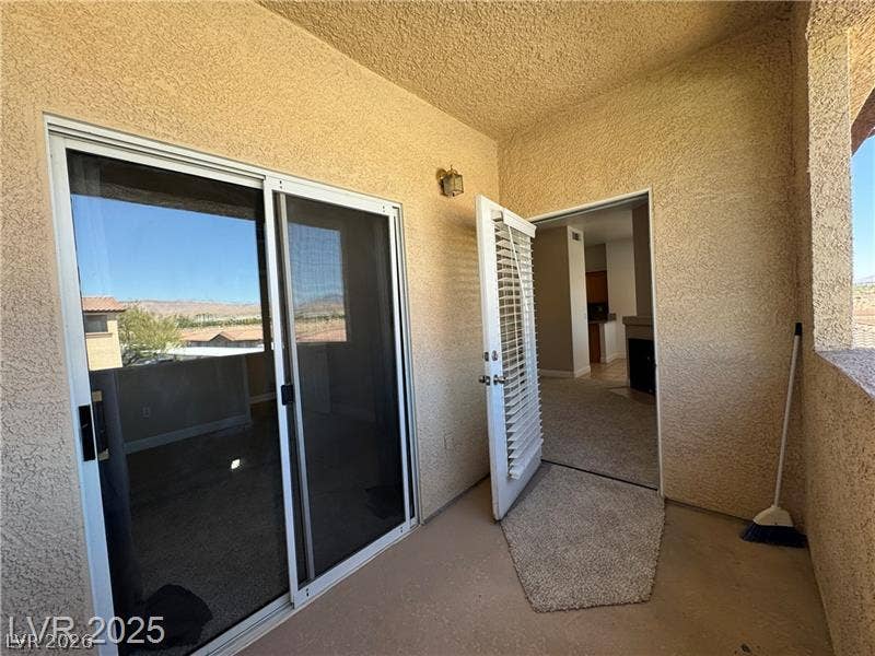Sliding glass doors open onto a private covered balcony finished with textured stucco walls.